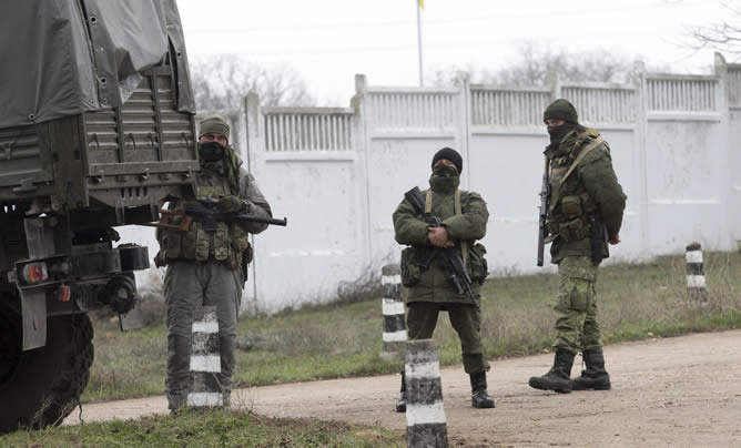 Varios hombres armados vestidos con uniformes militares vigilan el territorio de una unidad militar ucraniana en Sevastopol, en Crimea (Ucrania)