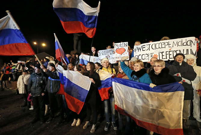 Unas personas sostienen banderas rusas mientras participan en una concentración para festejar la reunificación de Crimea con Rusia, en la plaza de Lénin en Simferópol, la capital de Crimea