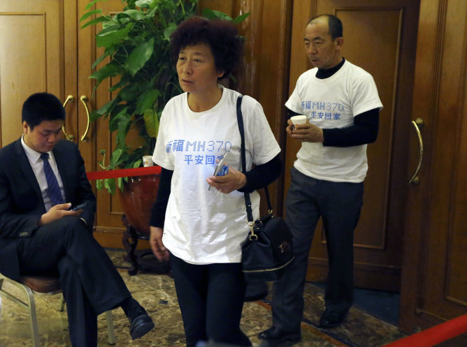 Familiares de los pasajeros de los desaparecidos del Malaysia Airlines saliendo de una conferencia con camisetas en las que piden que se ruegue por ellos