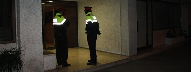 Dos agentes de los Mossos, en la entrada del edificio donde ha tenido lugar el crimen