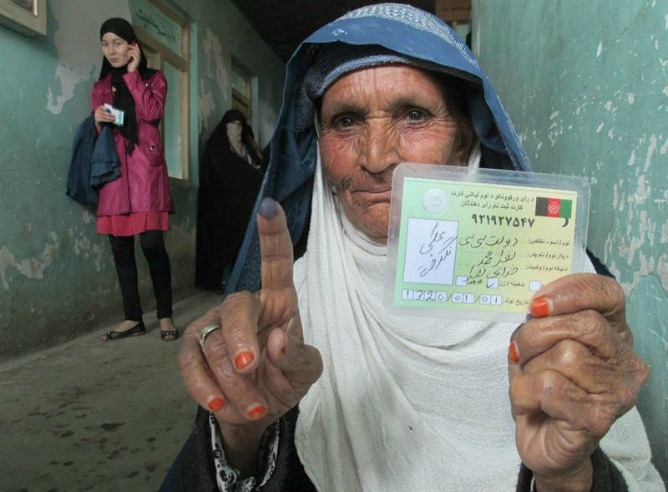Una ciudadana de Afganistán muestra su tarjeta de votante en la puerta de los colegios electorales