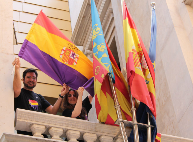Los diputados autonómicos Ignacio Blanco y Esther López colocando una bandera republicana en el balcón de Esquerra Unida en el Parlamento Valenciano
