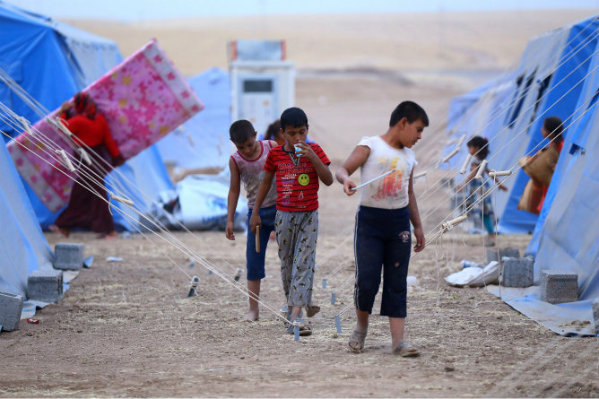 Un grupo de niños iraquíes caminan por un campamento de refugiados cerca a la ciudad de Erbil (Irak)