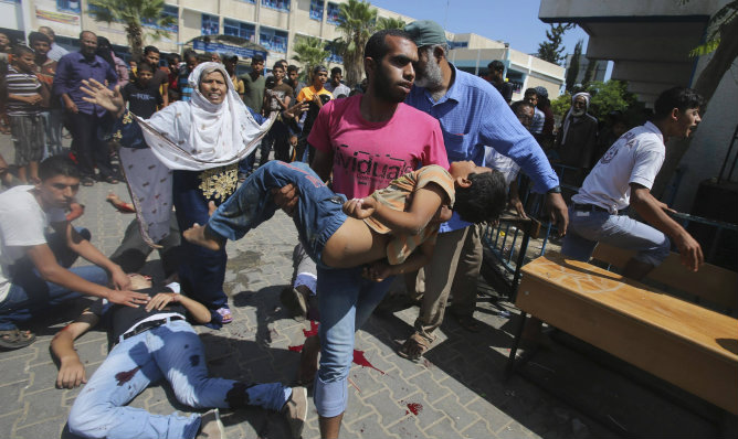 Un palestino acarreando el cuerpo de un niño tras el ataque Israelí en la escuela de la ONU en Rafah (Gaza)