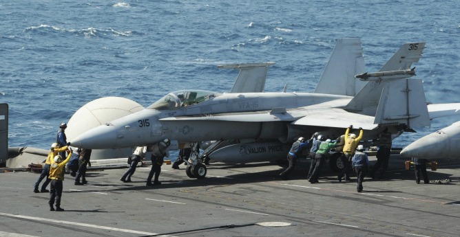 Varios miembros de la Marina guiando a un avión Hornet F/A 18 para su despegue.
