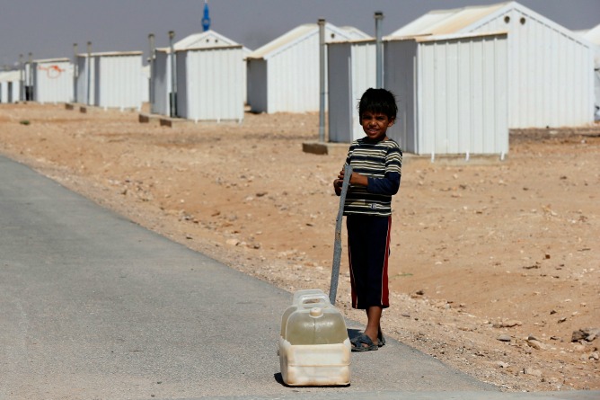 Un niño refugiado sirio saca un recipiente de agua en el campamento de refugiados cerca de Azraq, al este de Ammán