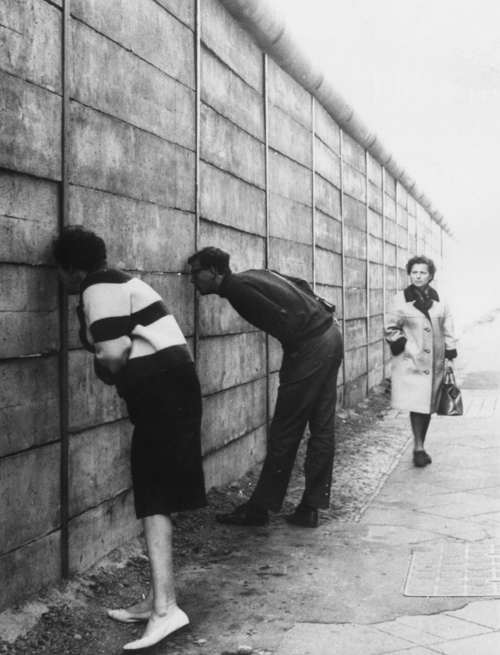 Berlineses occidentales mirando a través del Muro de Berlín en el sector oriente cerca de Check Point Charlie. La pared recién erigida no tiene alambre de púas. Los tubos hacen que sea difícil lograr un apoyo a alguien que trate pasar por encima. Imagen de archivo del 3 de octubre de 1966. Berlineses occidentales mirando a través del Muro de Berlín en el sector oriente cerca de Check Point Charlie. La pared recién erigida no tiene alambre de púas. Los tubos hacen que sea difícil lograr un apoyo a alguien que trate pasar por encima. Imagen de archivo del 3 de octubre de 1966.