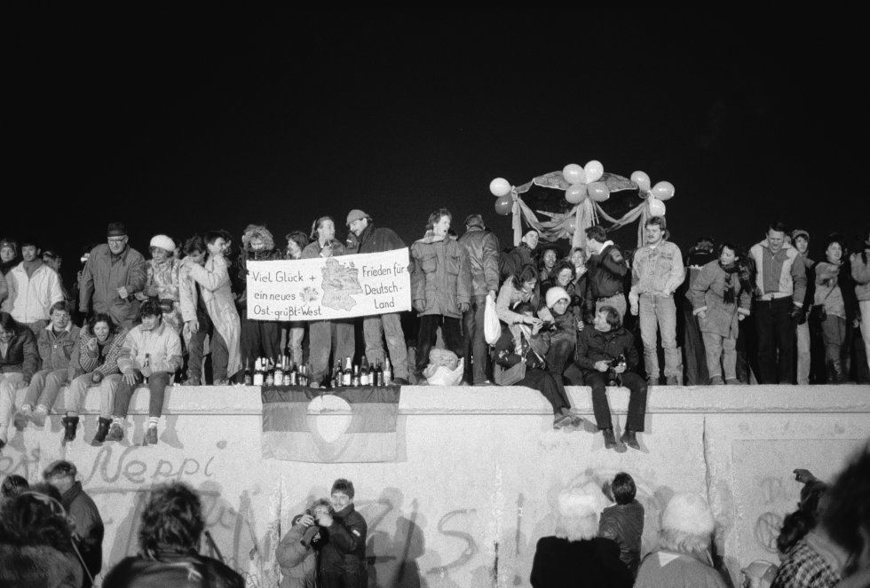 Los berlineses se reunieron en el Muro de Berlín para celebrar el Año Nuevo y el fin efectivo de la partición de la ciudad el 31 de diciembre de 1989. En la pancarta se lee "Buena suerte y paz para una nueva Alemania - el este saluda al oeste". Los berlineses se reunieron en el Muro de Berlín para celebrar el Año Nuevo y el fin efectivo de la partición de la ciudad el 31 de diciembre de 1989. En la pancarta se lee "Buena suerte y paz para una nueva Alemania - el este saluda al oeste".