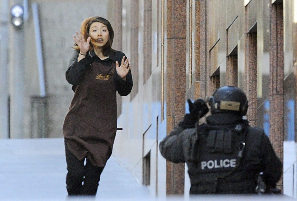 Una empleada abandona la cafetería donde trabaja y que un hombre armado tiene tomada desde primeras horas de la mañana en Sídney (Australia).