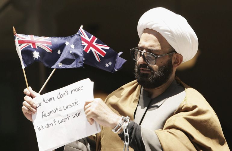 Man Haron Monis atado con cadenas y alzando dos banderas australianas a las puertas del juzgado Downing Centre después de ser condenado por amenazar por correo a familiares de militares australianos en Afganistán.