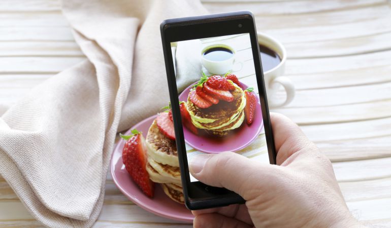 Imagen de recurso de un usuario fotografiando comida con su móvil