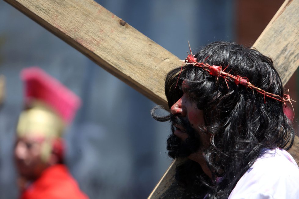 Un hombre caracterizado como Jesús carga una cruz de madera durante la representación de la pasión de cristo en un Vía Crucis en vivo en el municipio de Villa Nueva (Guatemala). Un hombre caracterizado como Jesús carga una cruz de madera durante la representación de la pasión de cristo en un Vía Crucis en vivo en el municipio de Villa Nueva (Guatemala).