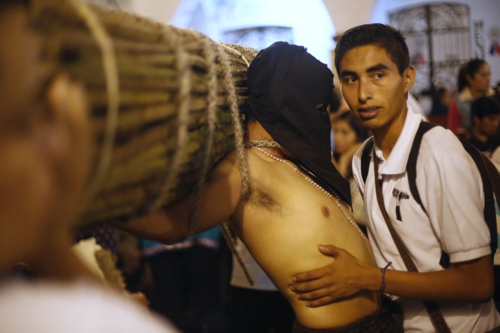Un hombre ayuda a un penitente mientras éste lleva una cruz a su espalda, en Taxco (México). Un hombre ayuda a un penitente mientras éste lleva una cruz a su espalda, en Taxco (México).