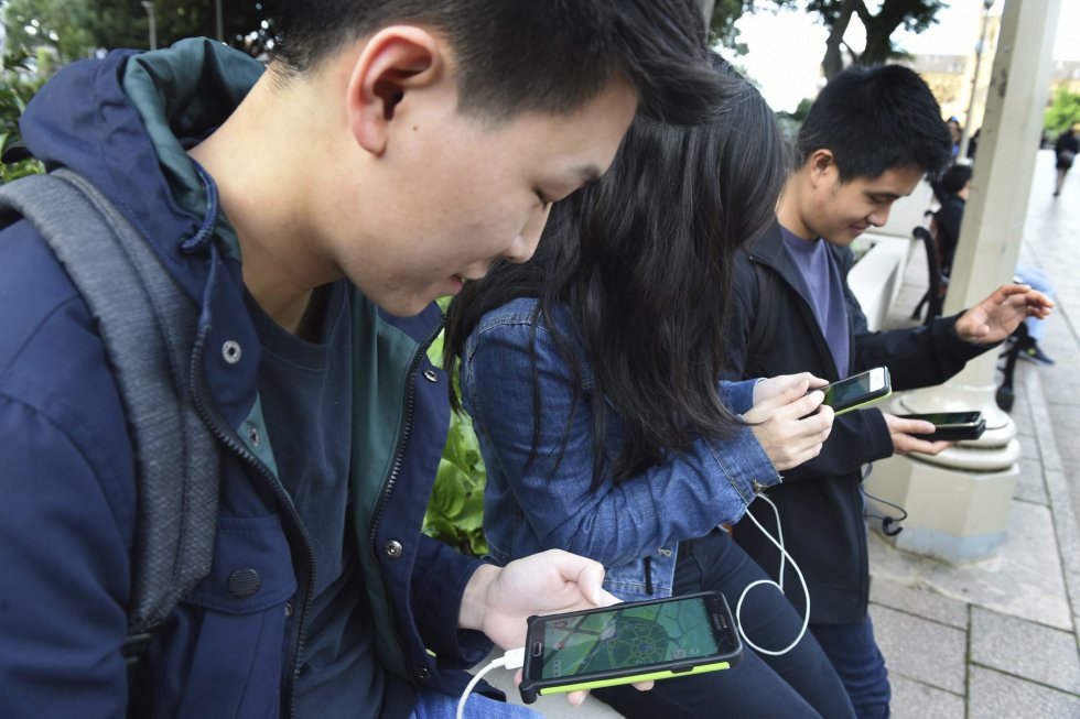 Unos estudiantes prueban el nuevo juego 'Pokémon Go' en su móvil en Melbourne (Australia).