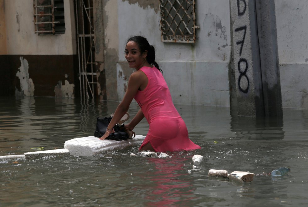 Una mujer utiliza una plancha para mantener secos sus zapatos mientras cruza una calle inundada en La Habana. Una mujer utiliza una plancha para mantener secos sus zapatos mientras cruza una calle inundada en La Habana.