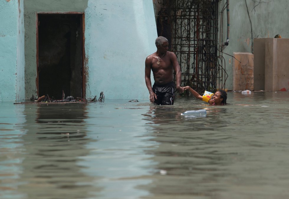 Un hombre sujeta a una niña con un flotador en una calle inundada de La Habana. Un hombre sujeta a una niña con un flotador en una calle inundada de La Habana.