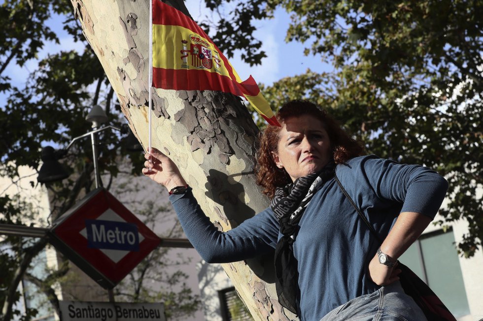 Una mujer porta una bandera española antes del inicio del desfile del Día de la Fiesta Nacional, al que asiste el Gobierno en pleno y la mayoría de líderes políticos. Una mujer porta una bandera española antes del inicio del desfile del Día de la Fiesta Nacional, al que asiste el Gobierno en pleno y la mayoría de líderes políticos.