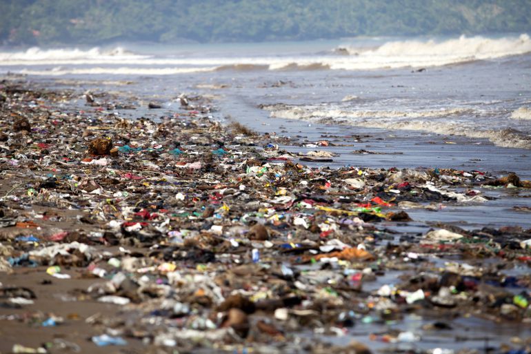 Esta imagen muestra una playa con un montón de plásticos tirados en la orilla.