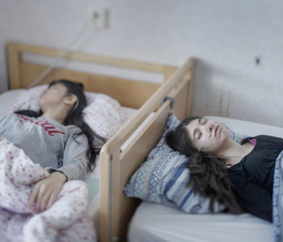 Fotografía captada por el fotógrafo Magnus Wennman, ganador del primer premio de la categoría 'People - Singles'. Muestra a Djeneta (d) postrada en cama y sin responder durante dos años y medio, y a su hermana Ibadeta, en la misma situación durante más de seis meses, gracias al uppgivenhetssyndrom (síndrome de resignación), en Horndal, Suecia, el 2 de marzo de 2017. Fotografía captada por el fotógrafo Magnus Wennman, ganador del primer premio de la categoría 'People - Singles'. Muestra a Djeneta (d) postrada en cama y sin responder durante dos años y medio, y a su hermana Ibadeta, en la misma situación durante más de seis meses, gracias al uppgivenhetssyndrom (síndrome de resignación), en Horndal, Suecia, el 2 de marzo de 2017.