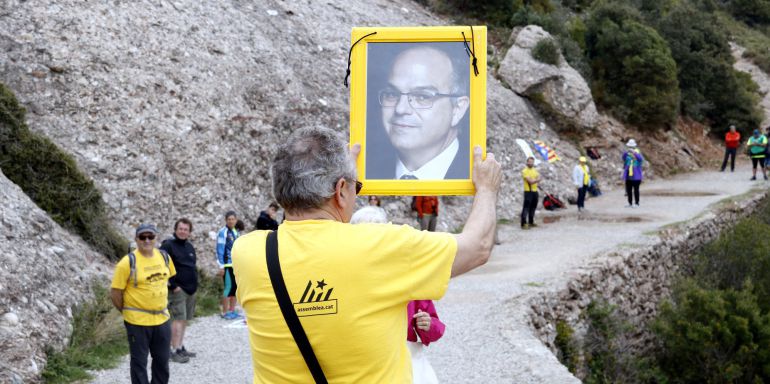 Un participant aixeca la fotografia de Jordi Turull abans de passar-la a una altra persona de la cadena. 28 d'abril de 2018. (Horitzontal)