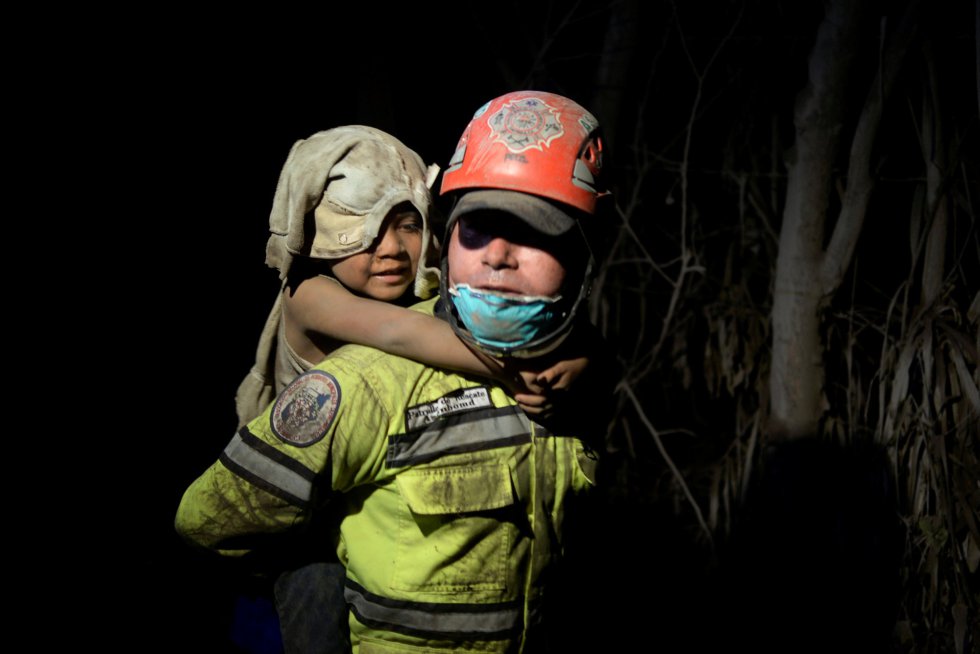 Un miembro de los equipos de emergencia rescata a un niño cubierto de la ceniza del volcán de Fuego. Un miembro de los equipos de emergencia rescata a un niño cubierto de la ceniza del volcán de Fuego.