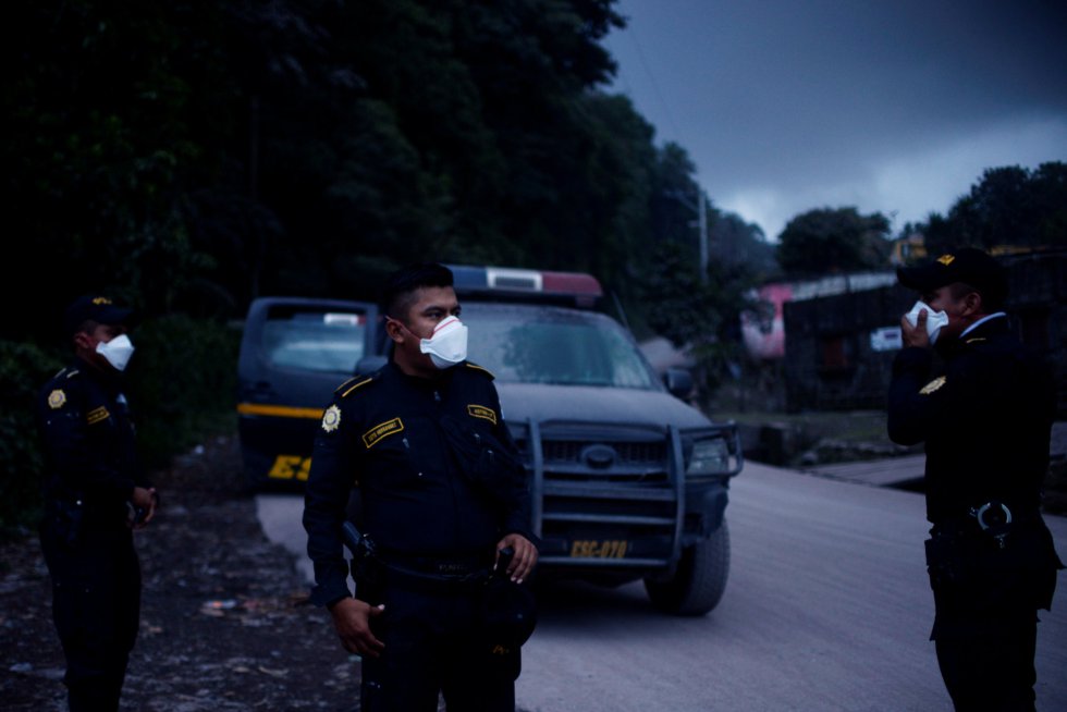 Un grupo de policías se cubren con máscaras para protegerse de los gases de la erupción volcánicas Un grupo de policías se cubren con máscaras para protegerse de los gases de la erupción volcánicas
