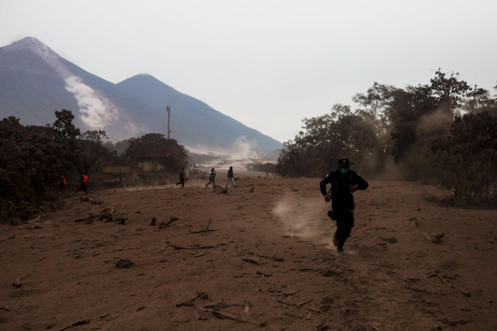 Un policía corre por un deslizamiento de fluido del volcán de Fuego después de la erupción Un policía corre por un deslizamiento de fluido del volcán de Fuego después de la erupción