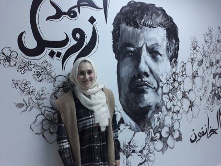 Nada Hashem junto al retrato del premio Nobel Ahmed Zaweil