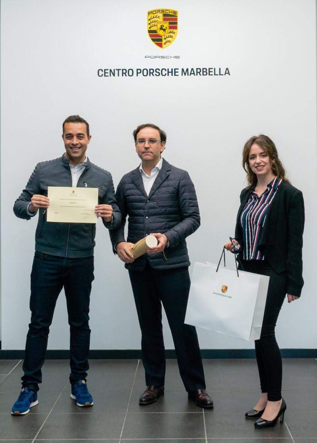Entrega de la acreditación como Embajador del Centro Porsche Marbella por parte de Rafael Rivero, Gerente de Centro Porsche Marbella y Rocío Laure, Responsable de Marketing
