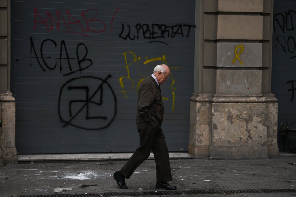 Un hombre camino delante de varias pintadas en la pared Un hombre camino delante de varias pintadas en la pared