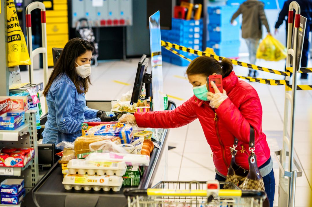 Una persona realiza la compra en un supermercado sujeta las medidas de seguridad