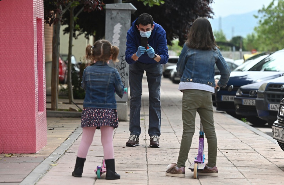 Un hombre hace una foto a sus hijas que han salido con patinetes a dar una vuelta por su barrio. Un hombre hace una foto a sus hijas que han salido con patinetes a dar una vuelta por su barrio.