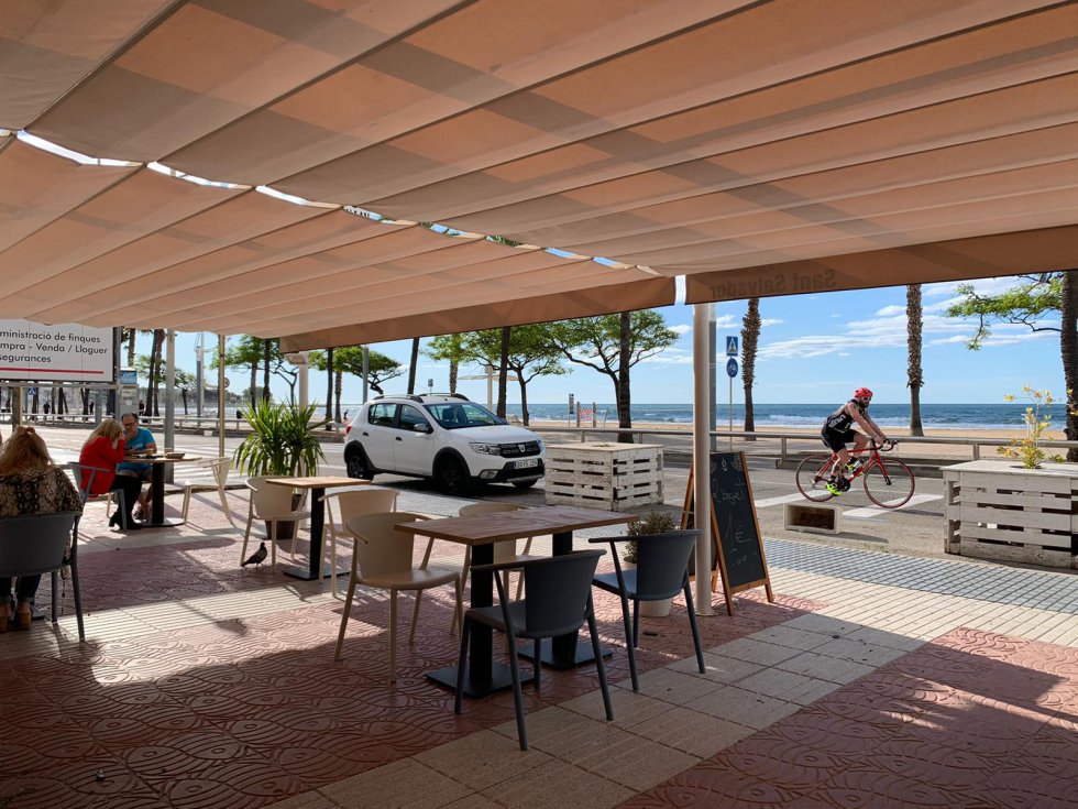Terraza en Cambrils con algún cliente. Mientras, un ciclista pasa por el paseo marítimo. Terraza en Cambrils con algún cliente. Mientras, un ciclista pasa por el paseo marítimo.