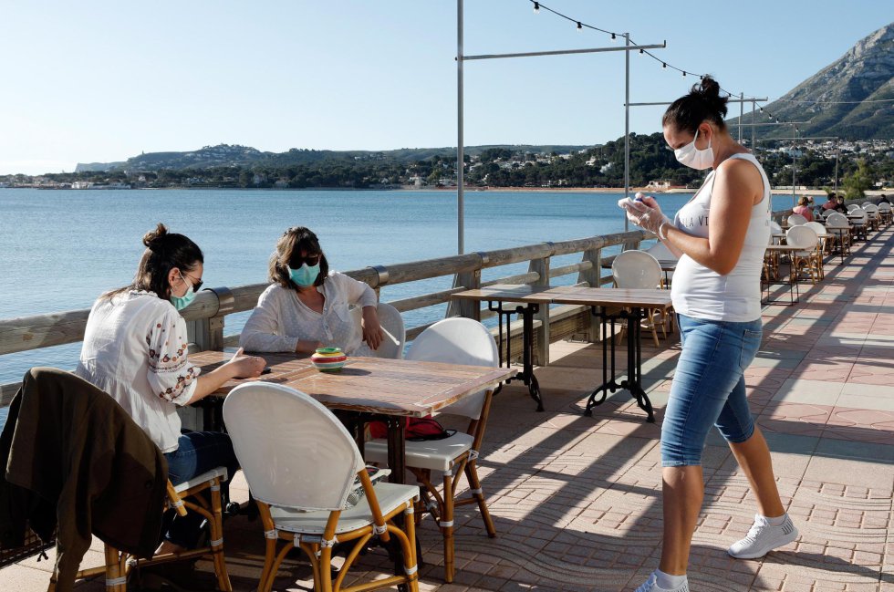 Una camarera atiende a dos clientas en una terraza en la localidad Alicantina de Denia, uno de los territorios de España que comienza la Fase 1. Una camarera atiende a dos clientas en una terraza en la localidad Alicantina de Denia, uno de los territorios de España que comienza la Fase 1.