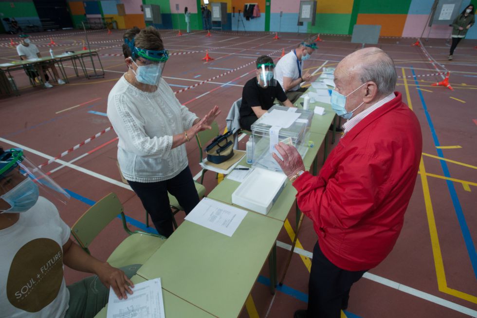 Un hombre muestra du DNI antes de depositar su voto en la urna manteniendo la distancia de seguridad con los miembros de la mesa electoral en un colegio de Burela (Lugo) Un hombre muestra du DNI antes de depositar su voto en la urna manteniendo la distancia de seguridad con los miembros de la mesa electoral en un colegio de Burela (Lugo)