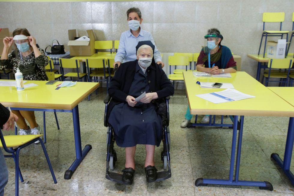 Una monja en silla de ruedas acude a votar a un colegio en Ribadeo (Galicia) con mascarilla y acompañada de otra mujer. Una monja en silla de ruedas acude a votar a un colegio en Ribadeo (Galicia) con mascarilla y acompañada de otra mujer.