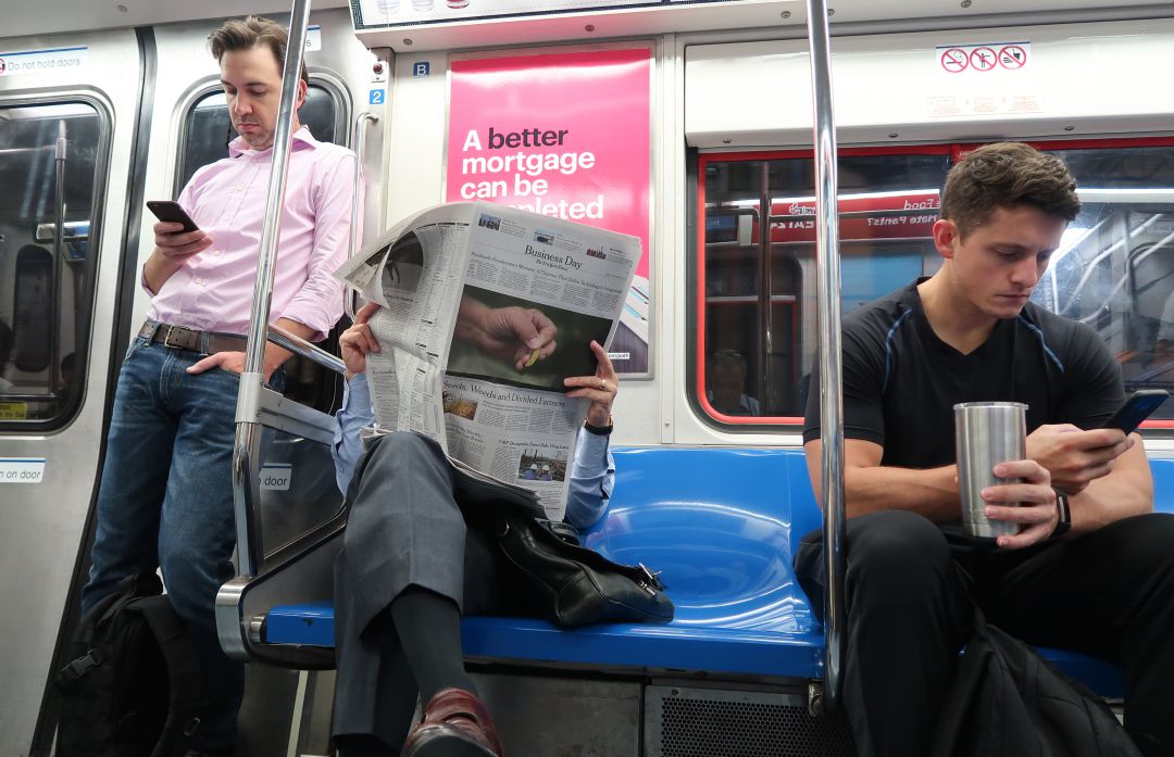 Psajeros del metro de Nueva York miran sus redes sociales o leen el periódico.