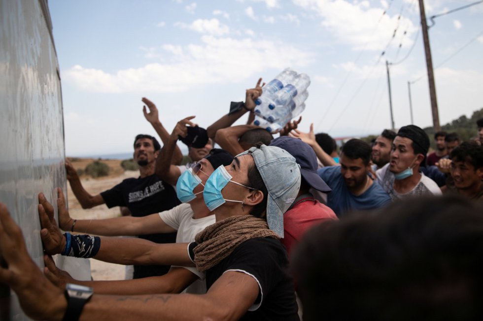 Migrantes reciben botellas de agua desde camiones en Lesbos. Migrantes reciben botellas de agua desde camiones en Lesbos.