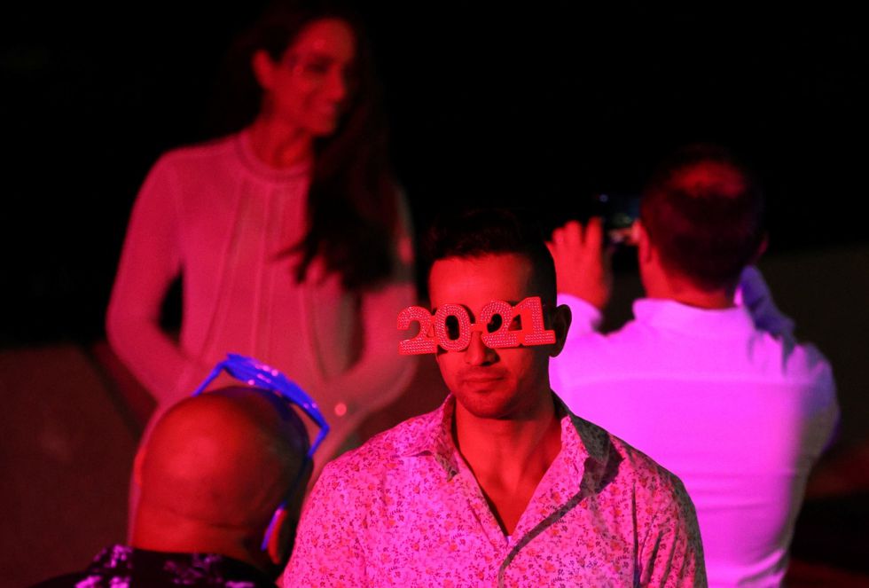 Un hombre con gafas de 2021 celebra la Nochevieja en la bahía de Sydney junto a un pequeño grupo de personas. Un hombre con gafas de 2021 celebra la Nochevieja en la bahía de Sydney junto a un pequeño grupo de personas.