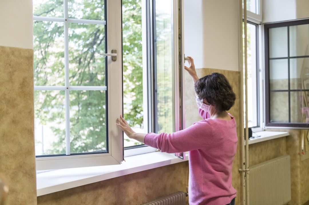 Una profesora abre las ventanas de una clase