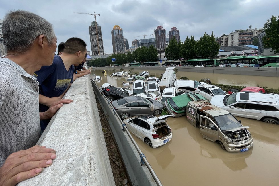 Un grupo de personas mira los coches acumulados en una riera en Zhengzhou. Un grupo de personas mira los coches acumulados en una riera en Zhengzhou.