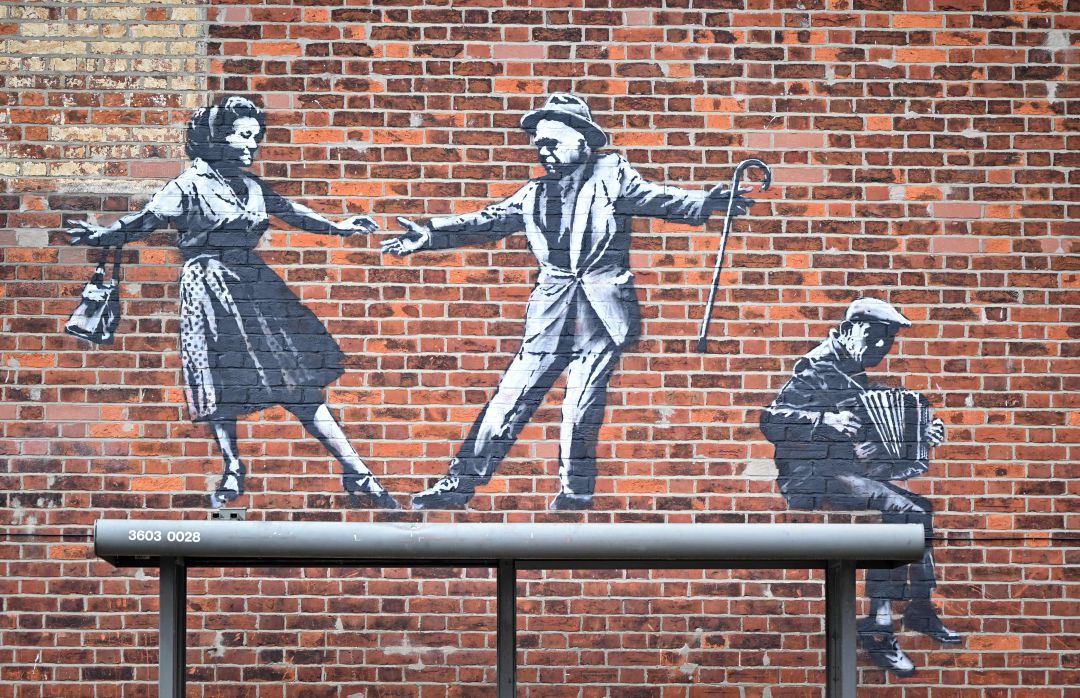 Obra de arte callejero que representa a una pareja bailando junto a un acordeonista en Great Yarmouth. 