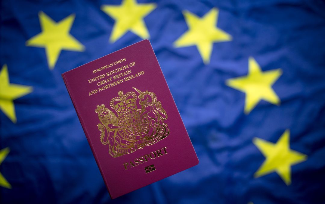 Un pasaporte británico con la bandera de la Unión Europea de fondo