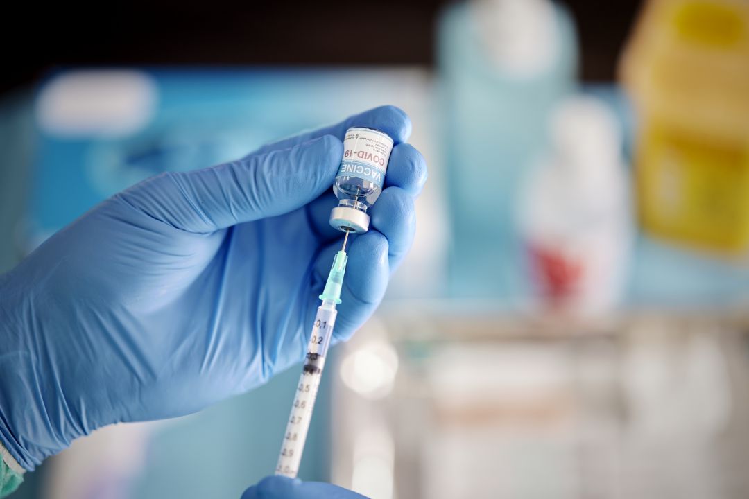Un trabajador sanitario poniendo el líquido de la vacuna contra la COVID-19 de un vial para vacunar a un paciente