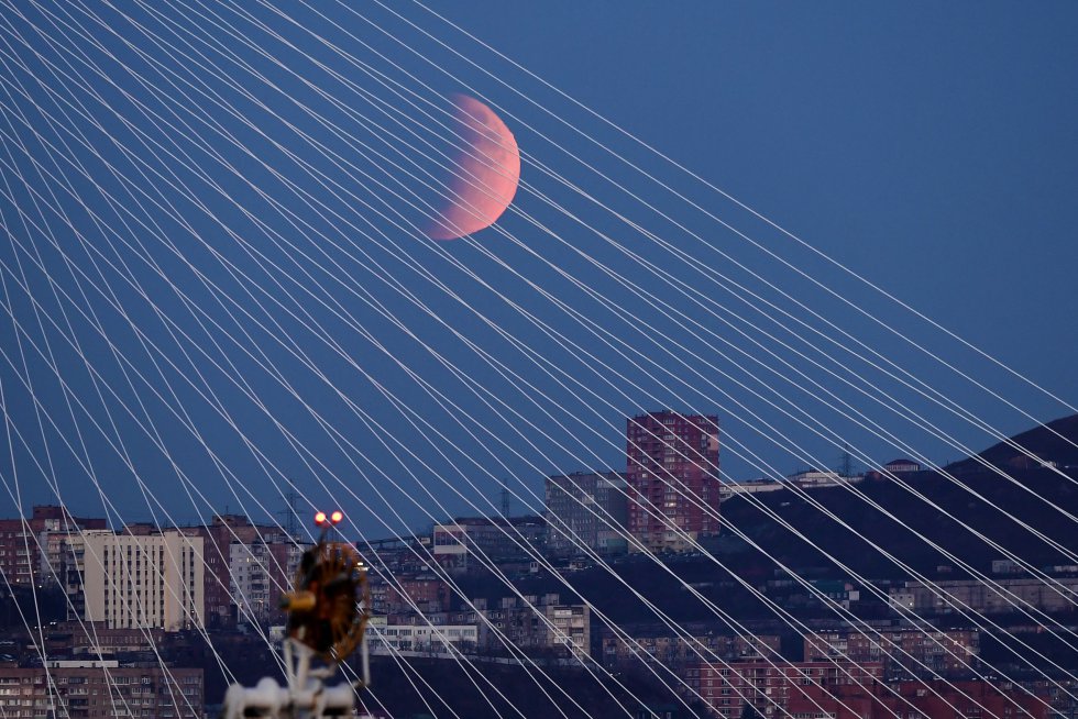 VLADIVOSTOK, RUSSIA - NOVEMBER 19, 2021: Vista del puente de Zolotoy durante el eclipse parcial lunar. VLADIVOSTOK, RUSSIA - NOVEMBER 19, 2021: Vista del puente de Zolotoy durante el eclipse parcial lunar.