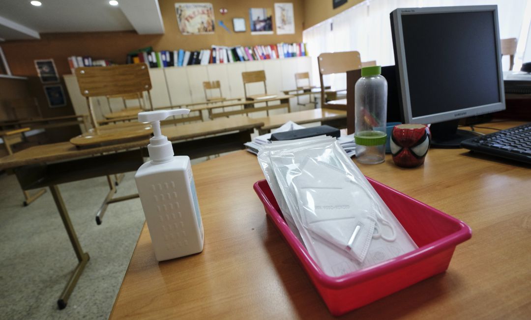 Imagen de archivo de mascarillas y gel desinfectante en la mesa del profesor de un aula.