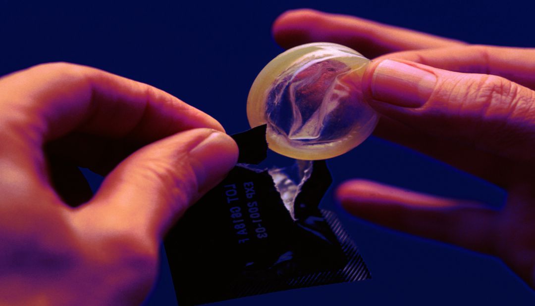 Una persona saca un preservativo de su envase.