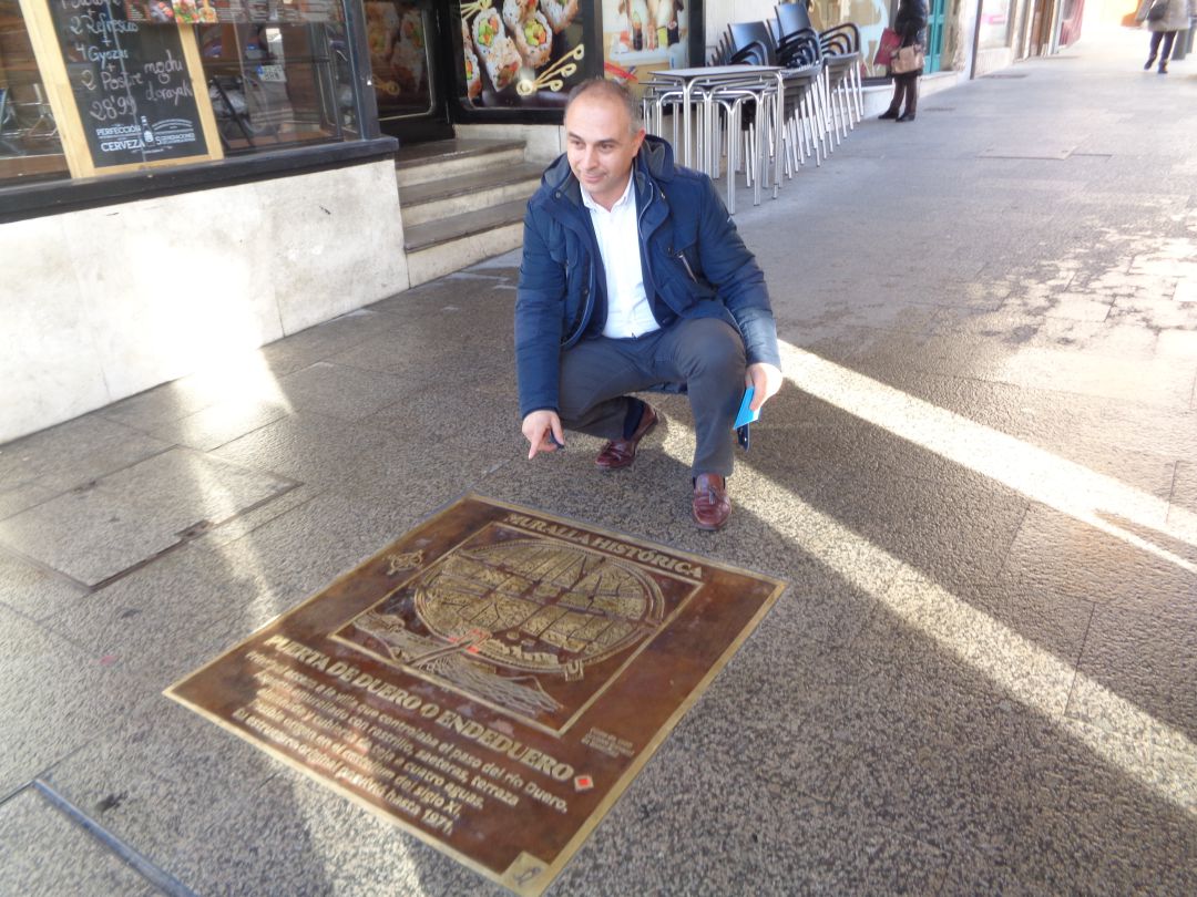 Emilio Berzosa muestra la placa que identifica a la Puerta Endeduero, el arco del Ayuntamiento, que marca el inicio del recorrido