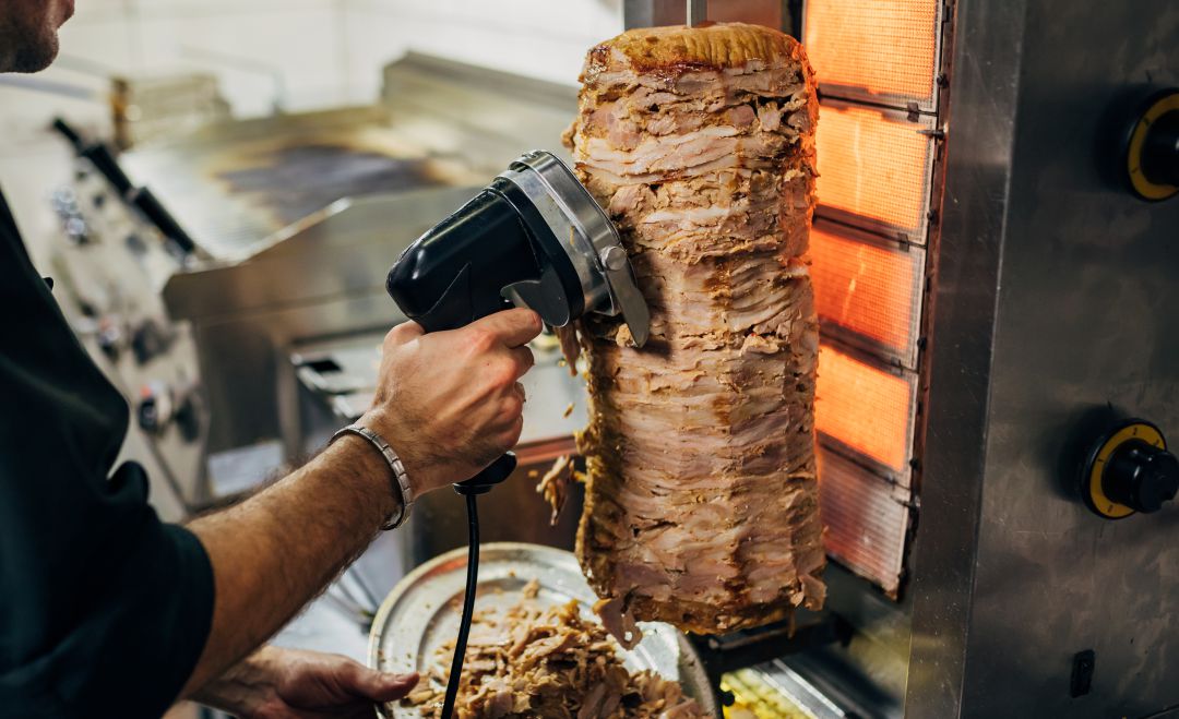 Un hombre corta carne para kebab.