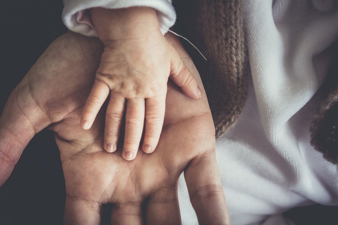 Imagen de una mano sosteniendo la de un bebé